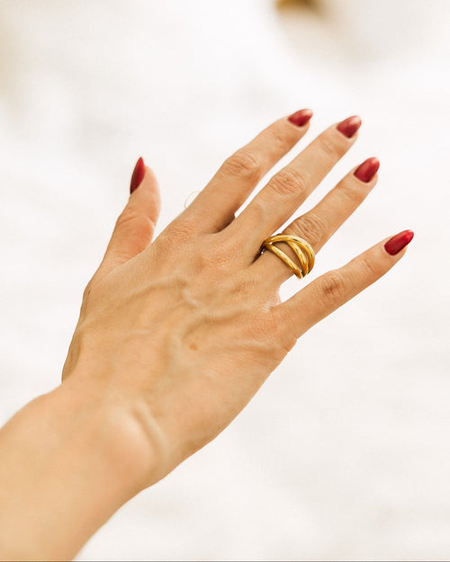 Gold-plated adjustable open-band ring worn on hand against white fabric