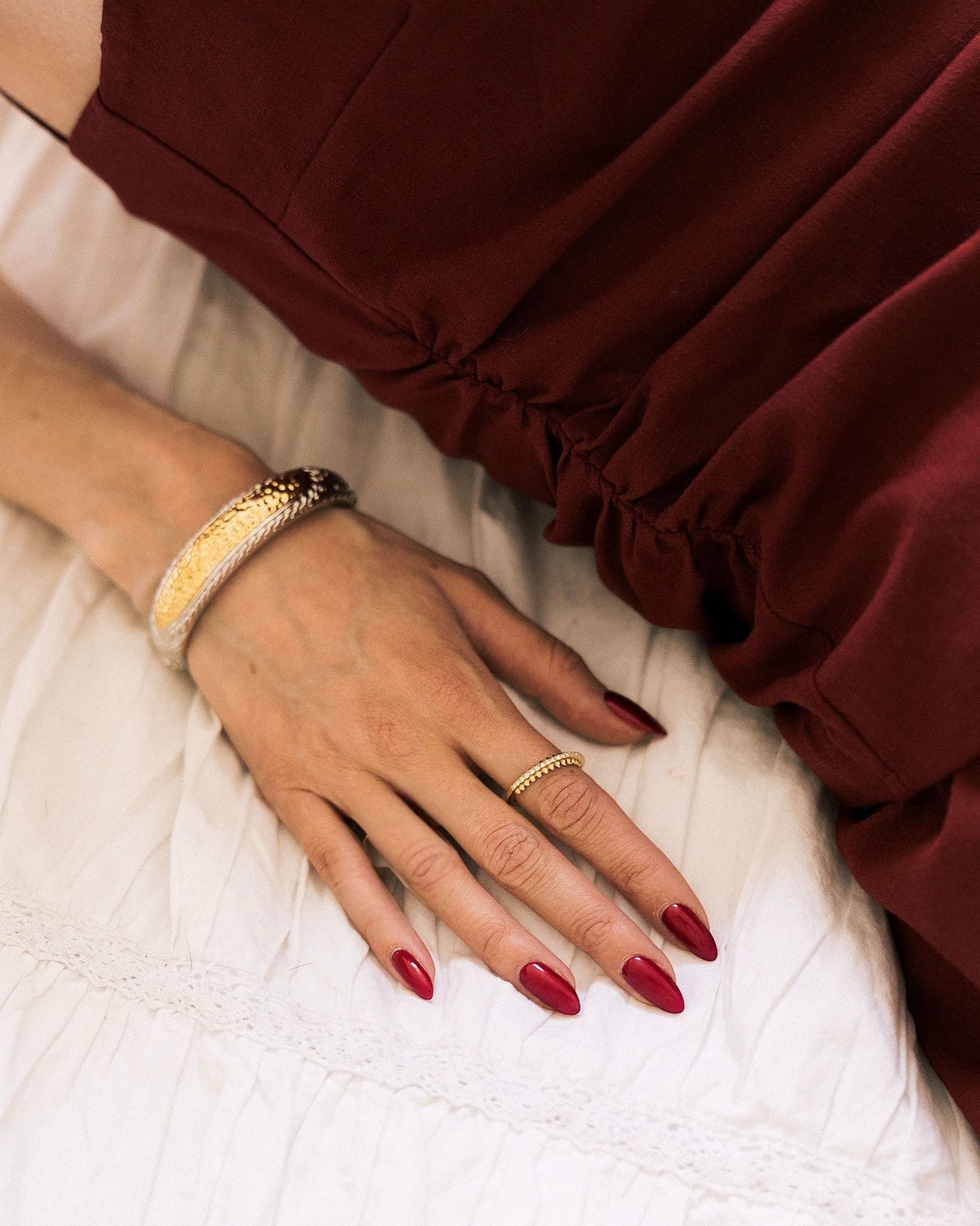 Crystal pavé ring gold-plated with rhinestones worn on hand with burgundy dress