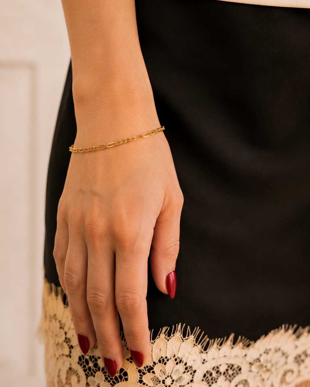 Minimalist Gold Chain Bracelet worn on wrist with red nails in black skirt and lace hem